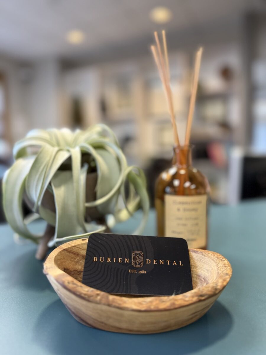 Burien Dental business cards displayed with plant and diffuser in office.