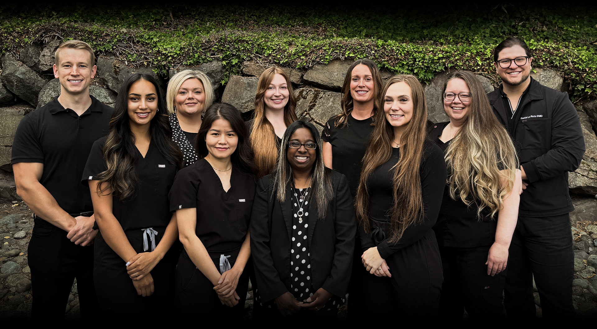 Team photo of staff at Burien Dental office in Burien, WA standing outside in front of a garden